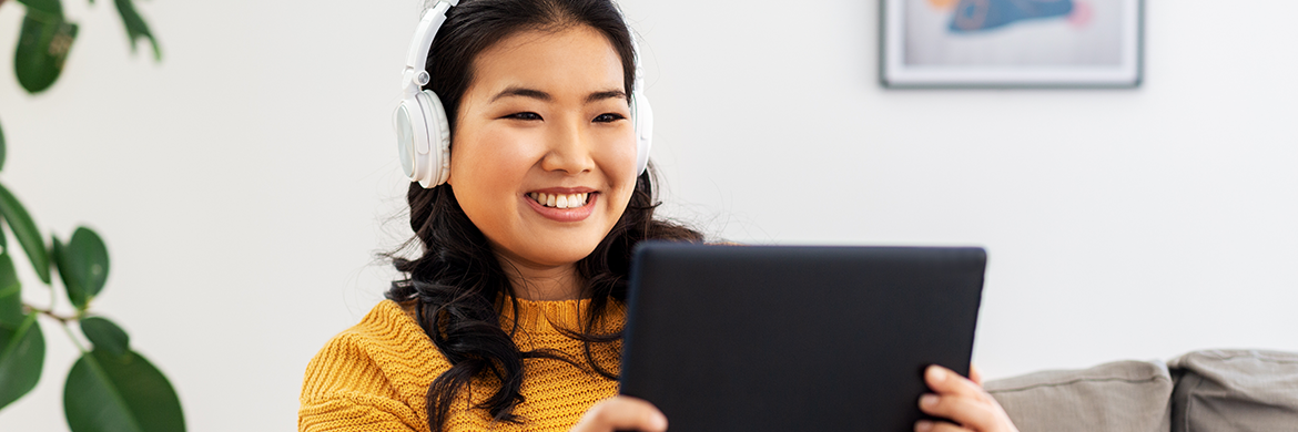 Woman smiling with headphones on and a tablet in her hands