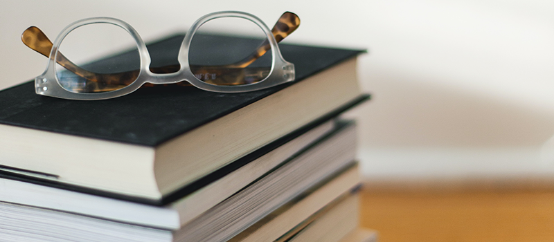 Stack of books with reading glasses placed on top