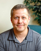 A man with close-cropped hair is smiling.