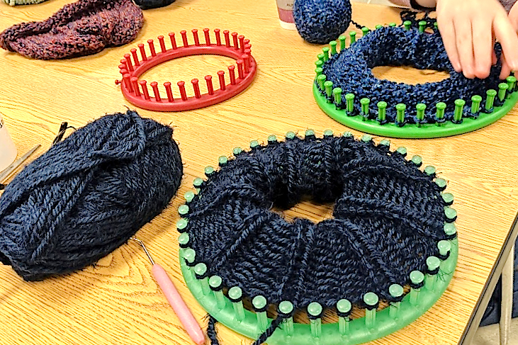 An assortment of circular knitting looms with works in progress loaded on.