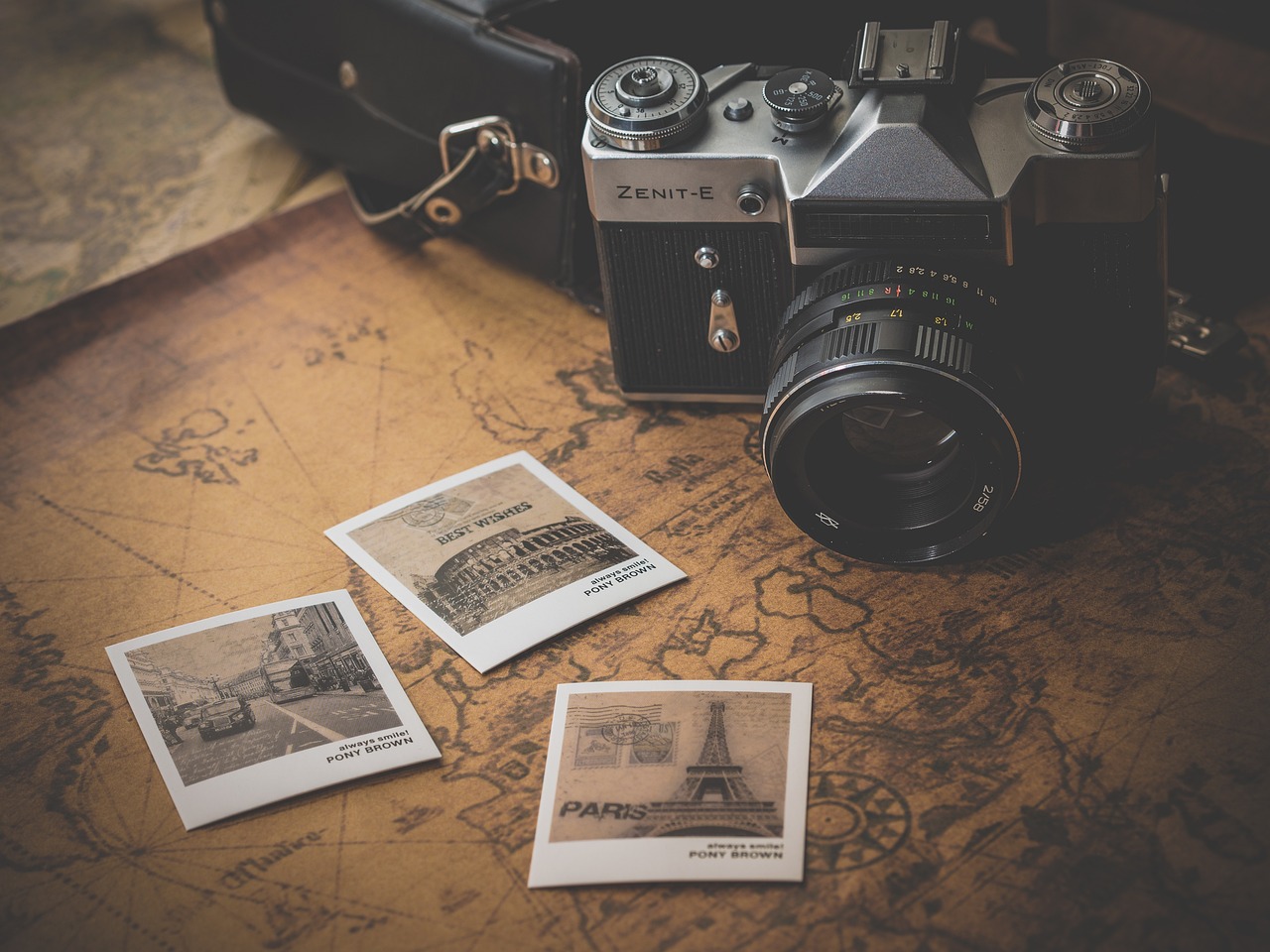 A camera and scattered photographs sitting on a desk.