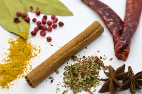 An assortment of herbs and spices in their natural state, including whole bay leaves, stick cinnamon, star anise, and dried chilis.