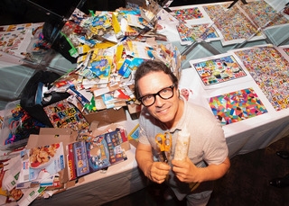 A man with glasses standing in front of a work surface that is covered in post-consumer packaging