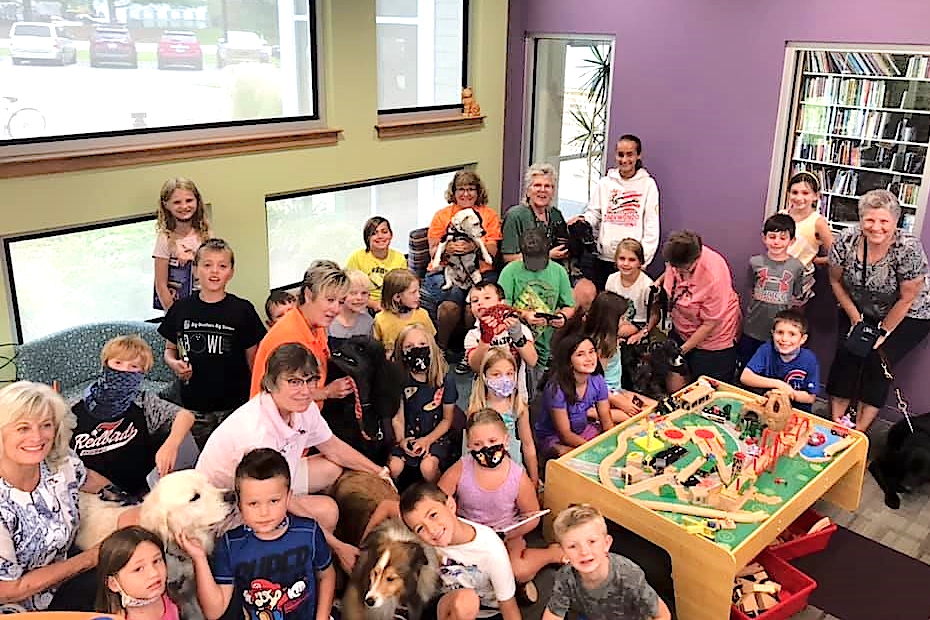 A large group of people of all ages posing with a variety of dogs.