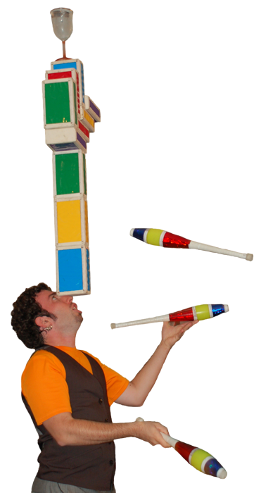 A man juggling three clubs while balancing a tower of blocks on his nose.  