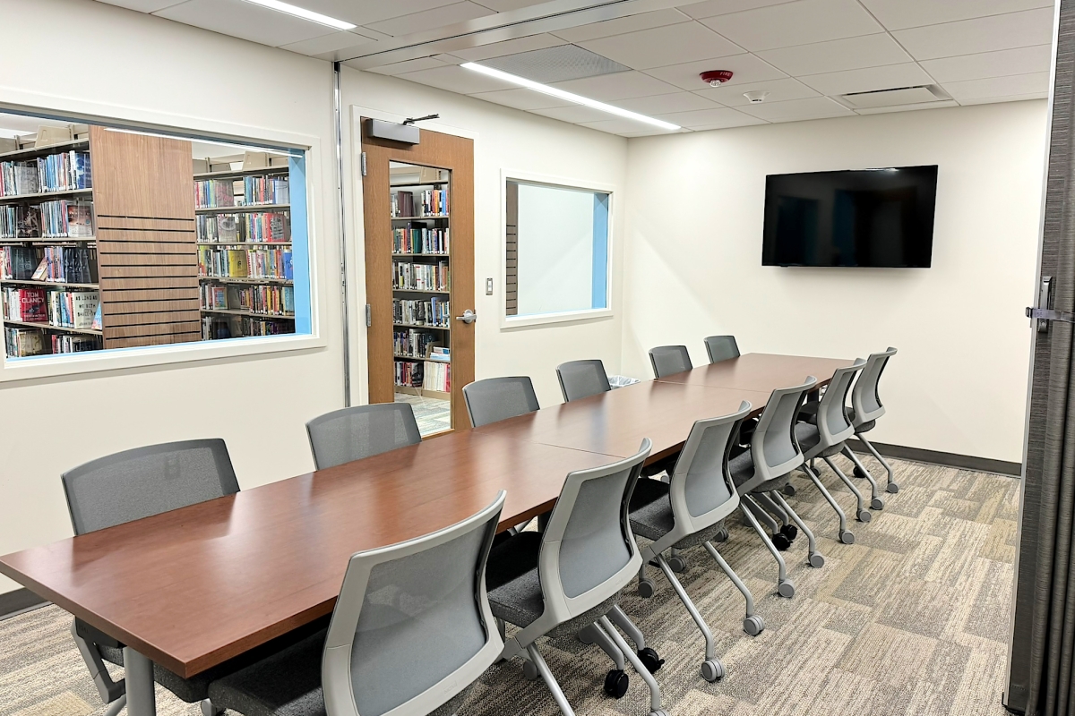 A meeting room with three tables and twelve chairs.  