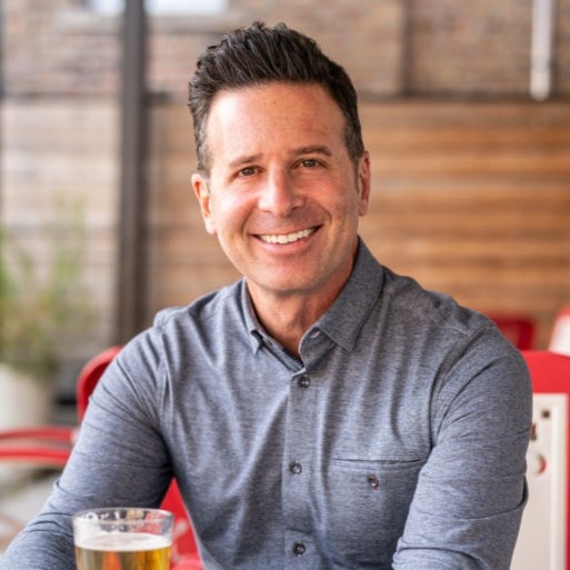 A smiling man is sitting in a restaurant. 