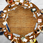 Computers and people sitting around a round wooden table