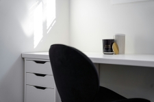 Black chair and white desk in a small room