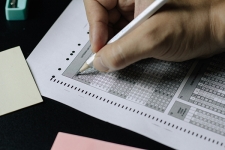 Hand holding a pencil and filling in bubbles on a scantron paper test