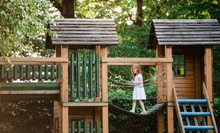 Girl walking across a drawbridge in a playground structure