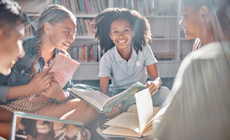 Group of five children sitting in a circle reading